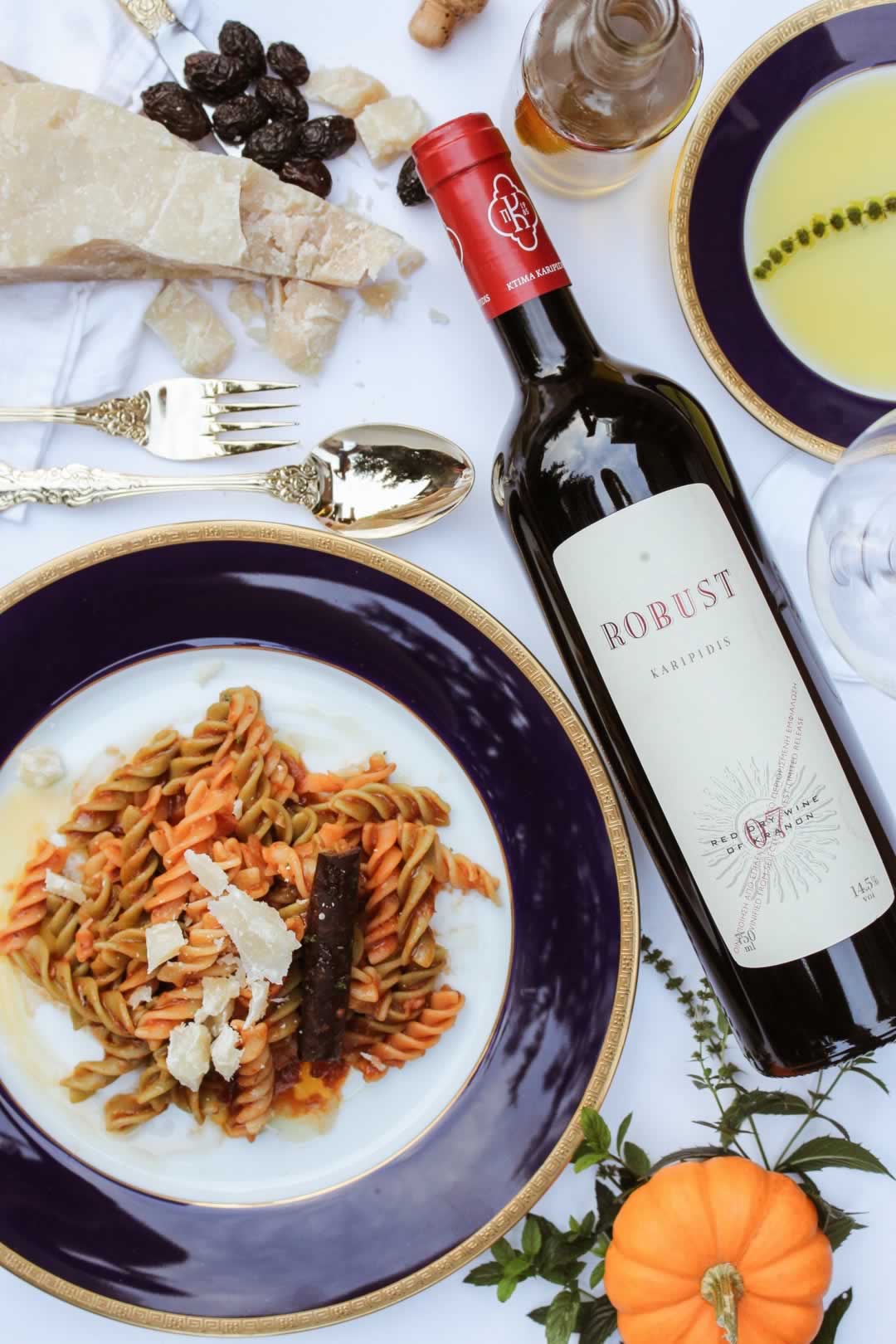 A table set for a meal with pasta, wine and fine crockery